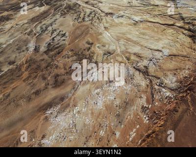 Aerial view of the exposed red earth landscape and winding stream of ...