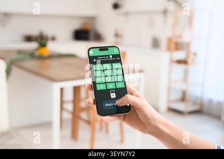 Person using smartphone app to control home alarm system Stock Photo