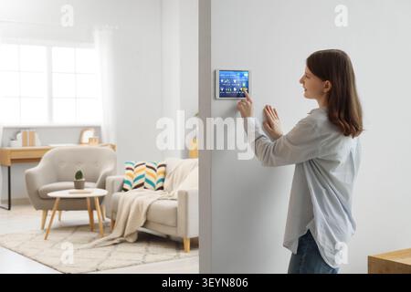 Woman using smart home control panel in living room Stock Photo