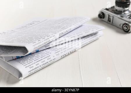Folded newspapers on white wooden table with vintage camera Stock Photo
