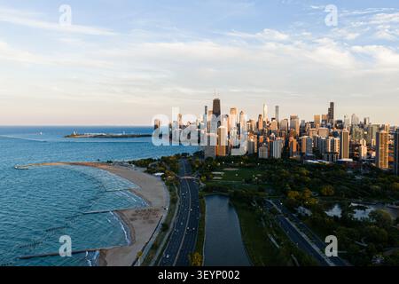 serene aerial drone shot of the chicago skyline with beachfront and cityscape in the background, featuring concrete, glass, and metal structures under Stock Photo