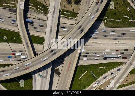 dynamic aerial view of urban freeway interchange with cars and highway overpasses in gray concrete and asphalt setting, showcasing vibrant traffic Stock Photo