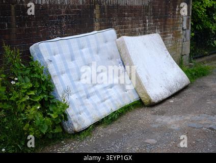 Old Mattresses Fly-Tipped (Dumped) In An Alleyway In The UK Stock Photo