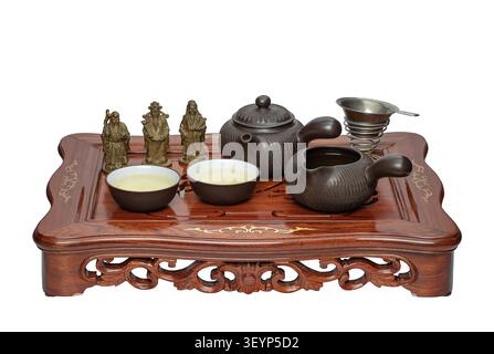 Chinese Gongfu tea set with ceramic teapot, teacups, tea strainer and figurines on wooden chaban tray, isolated on white background. Stock Photo