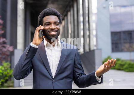 Confident businessman connecting with a client, smiling while discussing important business over a smartphone call outdoors in an urban environment, embodying communication and success Stock Photo