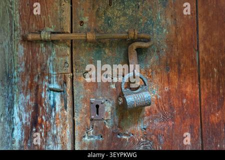 Old sliding bolt lock with padlock on antique wooden door Stock Photo