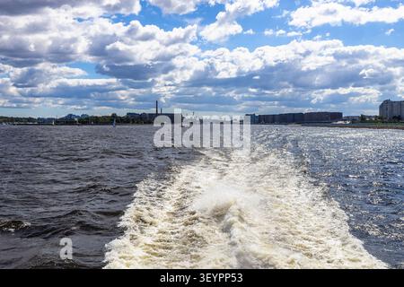 trail left in water of Neva River by moving boat in St Petersburg city on a sunny cloudy day Stock Photo