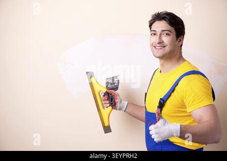Young contractor employee applying plaster on wall Stock Photo