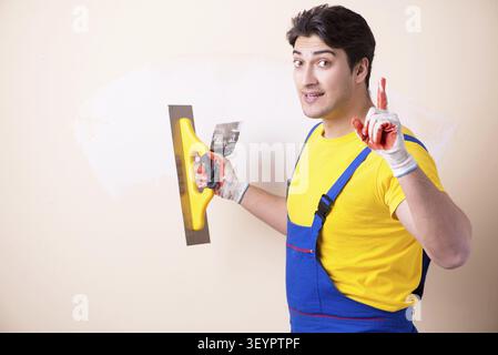 Young contractor employee applying plaster on wall Stock Photo