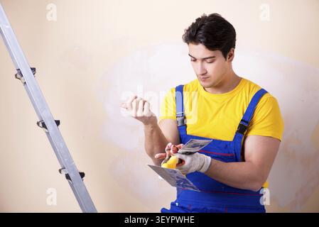Young contractor employee applying plaster on wall Stock Photo