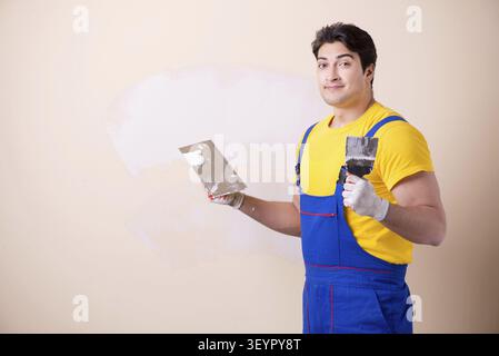 Young contractor employee applying plaster on wall Stock Photo