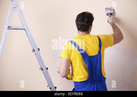 Young contractor employee applying plaster on wall Stock Photo