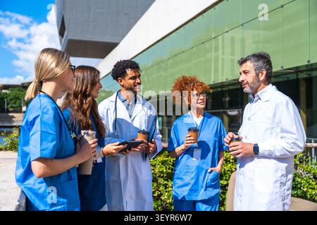 Diverse healthcare team workers collaborating and discussing outdoors Stock Photo