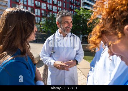 Medical team collaborating discussing healthcare services outdoors Stock Photo