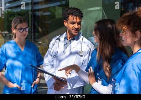 Diverse medical team collaborating on healthcare discussion outdoors Stock Photo