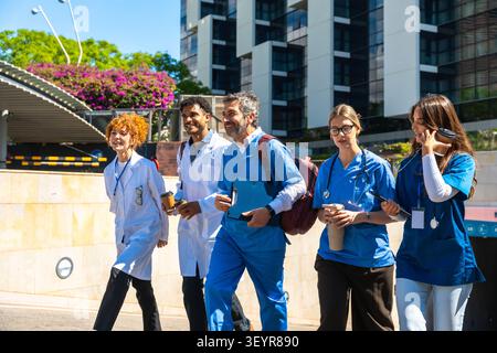 Diverse medical staff team walking outdoors collaborating on healthcare Stock Photo