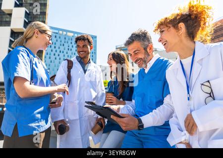 Diverse medical staff team discussing health concepts outdoors Stock Photo