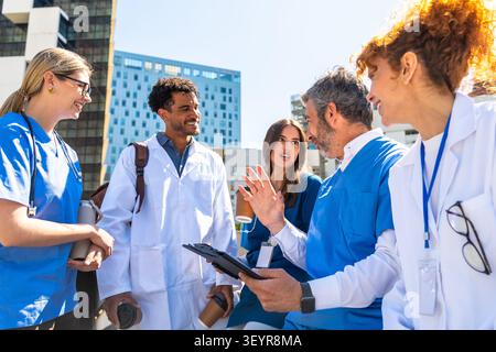 Diverse medical team collaborating outdoors discussing patient care Stock Photo