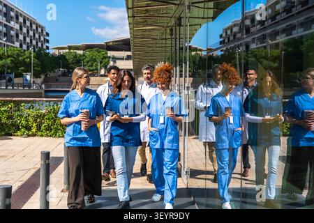 Diverse medical team walking together outside hospital building Stock Photo
