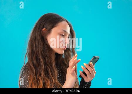 Young woman focused on browsing her smartphone in a professional photo studio... Stock Photo