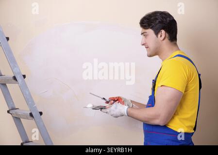 Young contractor employee applying plaster on wall Stock Photo