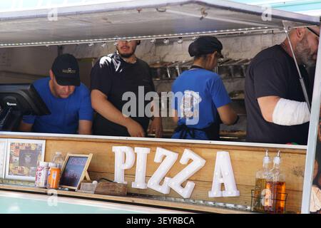 Busy pizza food truck kitchen with several chefs and staff members preparing orders at the popular Southsea Food Festival in Portsmouth, England. Stock Photo