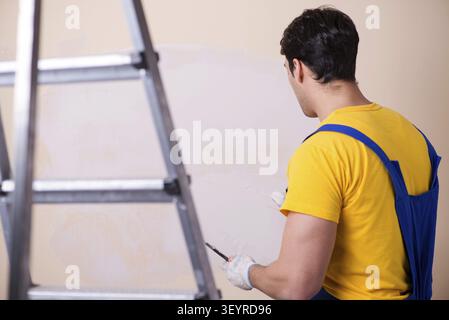 Young contractor employee applying plaster on wall Stock Photo
