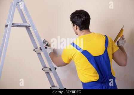 Young contractor employee applying plaster on wall Stock Photo