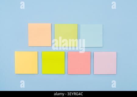 Seven colorful sticky notes are arranged in two rows on a blue background. The top row has three notes, and the bottom row has four. Stock Photo