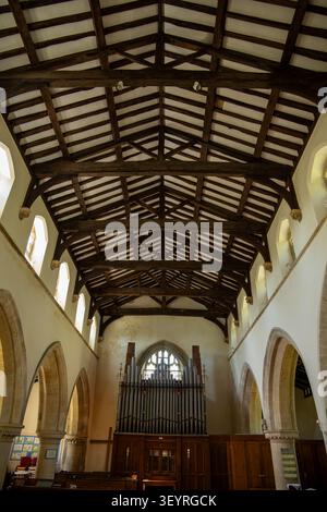 Interior view of a historic church nave showing the exposed timber beam roof ceiling construction and organ St Mary's church Collingbourne Kingston Stock Photo