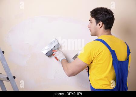 Young contractor employee applying plaster on wall Stock Photo