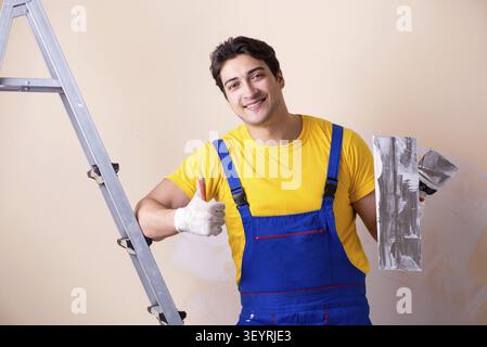 Young contractor employee applying plaster on wall Stock Photo