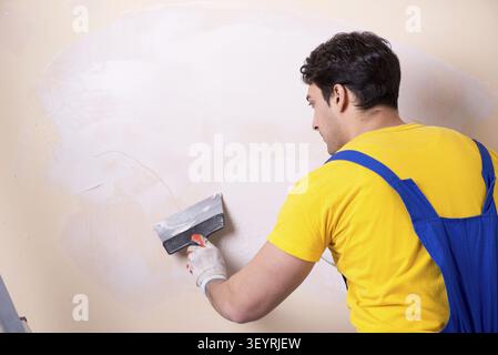 Young contractor employee applying plaster on wall Stock Photo