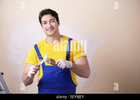 Young contractor employee applying plaster on wall Stock Photo