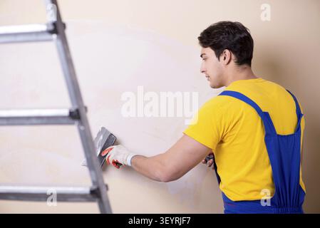 Young contractor employee applying plaster on wall Stock Photo