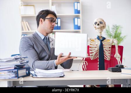Businessman working with skeleton in office Stock Photo
