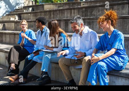 Diverse medical team collaborating and discussing healthcare outdoors Stock Photo