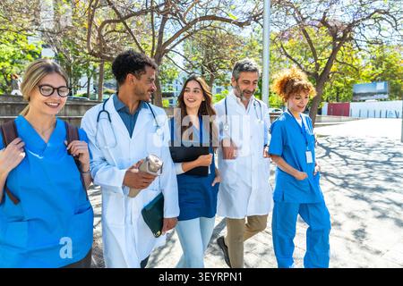 Diverse healthcare professionals walking together discussing medical topics Stock Photo