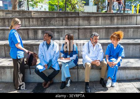 Diverse medical students and healthcare professionals conversing on campus Stock Photo