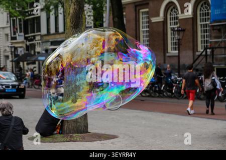 Large iridescent soap bubble floating along a street in central Amsterdam, Netherlands. Stock Photo