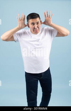 Young man making a funny face and touching his head playfully Stock Photo