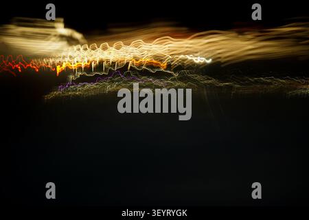 Abstract light painting fine art background featuring golden, red, and purple neon trails on black. Stock Photo