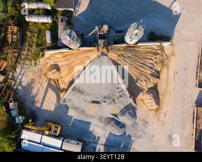 Aerial view of an industrial gravel and sand processing facility with large storage silos, piles of aggregate, and heavy machinery in Ravadinovo, Burg Stock Photo