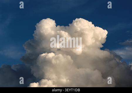 Beautiful large cumulus cloud structure glowing under sunlight against deep blue sky backdrop Stock Photo