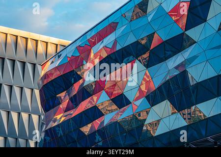Modern architectural structure, featuring geometric facade, triangular panels, reflective material, vibrant colors, golden hour lighting, intricate de Stock Photo