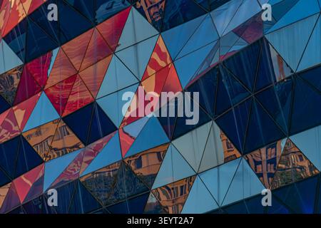 Architectural facade featuring triangular panels, vibrant colors, geometric pattern, urban reflections, modern design, contemporary aesthetics Stock Photo