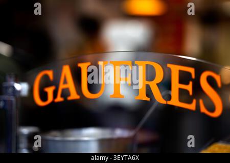 Dijon France July 2 2026. An orange waffle sign is seen on the glass window of a mobile street food truck. Various kitchen appliances and utensils are Stock Photo