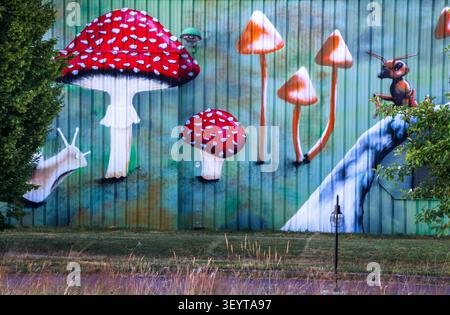Dijon France July 2 2026. Vibrant graffiti art featuring giant mushrooms, huge ants and butterflies is painted on a low factory corrugated metal profi Stock Photo