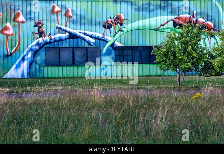 Dijon France July 2 2026. Vibrant graffiti art featuring giant mushrooms, huge ants and butterflies is painted on a low factory corrugated metal profi Stock Photo