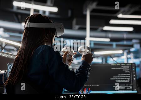 Server facility computing specialist programming equipment working with virtual reality technology. Server environment IT expert working with VR headset tech to update AI systems. Stock Photo